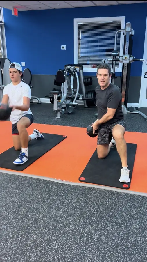 Two clients practicing half-kneeling medicine-ball exercises during partner training