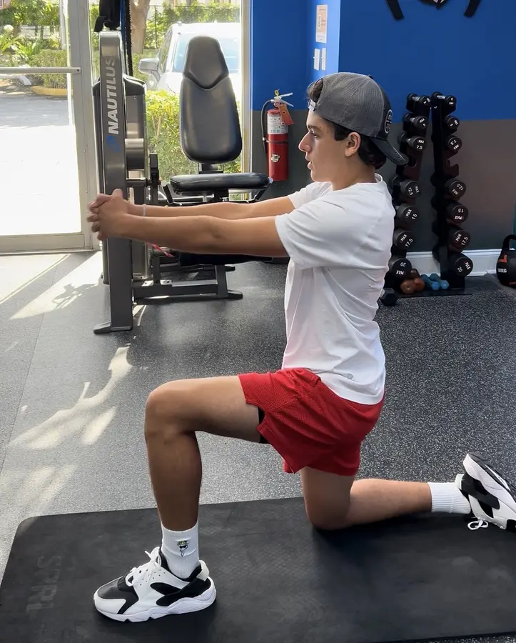 Client practicing a half-kneeling strength exercise in the studio